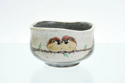 Ceramic cup with painted birds on a branch against a white background