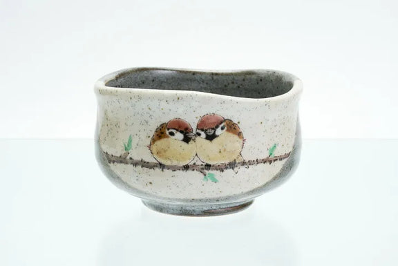 Ceramic cup with painted birds on a branch against a white background