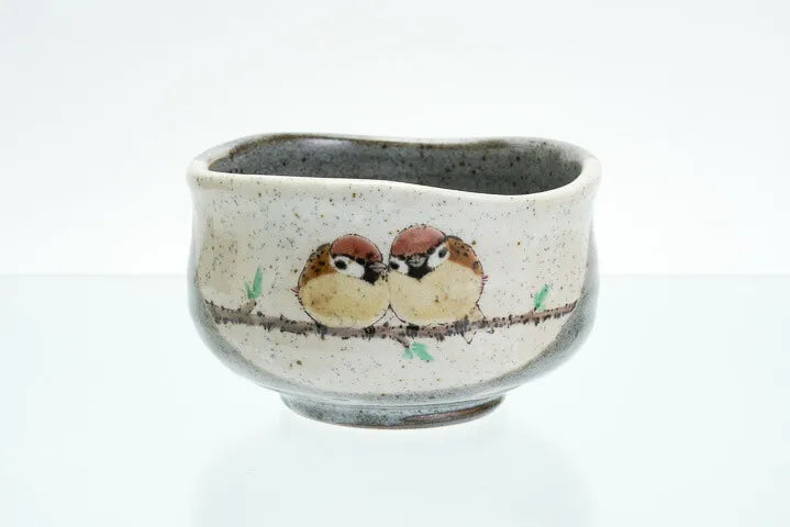 Ceramic cup with painted birds on a branch against a white background
